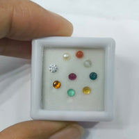 Small white box with various gemstones held by a hand against a white background